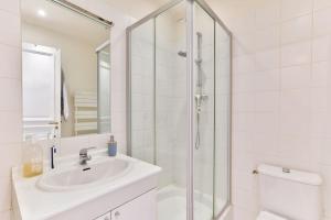 ein weißes Bad mit einem Waschbecken und einer Dusche in der Unterkunft Appartement 140m2 proche des Champs Elysées in Paris