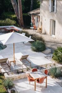 a patio with a table and chairs and an umbrella at Le Château Réal in Saint-Seurin-de-Cadourne