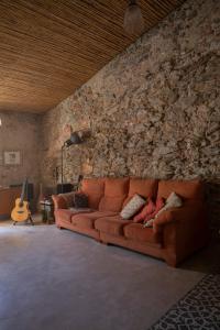 um sofá numa sala de estar com uma parede de pedra em Traditional House (renovated) 150m from the sea em Roses