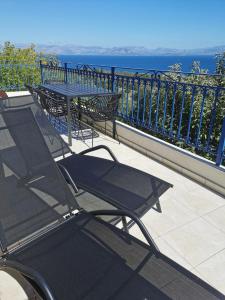 een tafel en stoelen op een balkon met uitzicht op de oceaan bij Peacefull Sea View Maisonette in Petrití