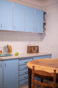 cocina con armarios azules y mesa de madera en Traditional House (renovated) 150m from the sea, en Roses