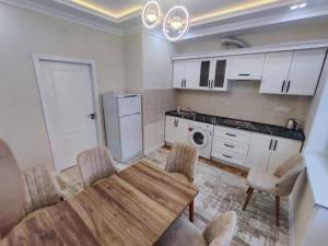 a kitchen with a wooden table and chairs in a room at Golden Apartments in Khujand