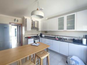 uma cozinha com armários brancos e uma mesa de madeira em Bayside Holiday Home em São Martinho do Porto
