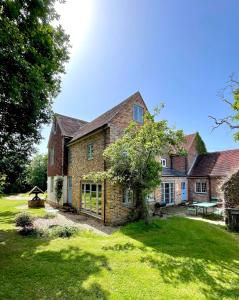 une grande maison en briques avec une cour d'herbe dans l'établissement Starnash Farmhouse Holiday Home, à Hailsham