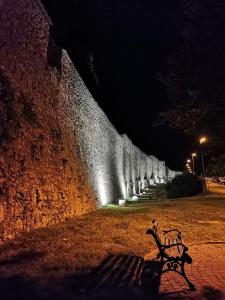 a park bench sitting next to a wall at night at Casa del Palazzo del Marchese in Tarquinia +6 photos