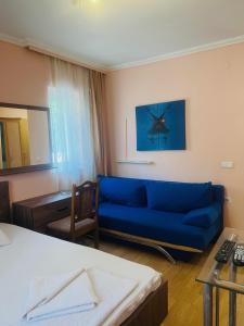 a living room with a blue couch and a desk at Guest House Velania in Pristina