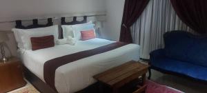 1 dormitorio con 1 cama grande y 1 silla azul en Mmathaba Guest House en Mmadinare