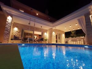 Donji Babići的住宿－Villa Santo，夜间在房子里的一个游泳池