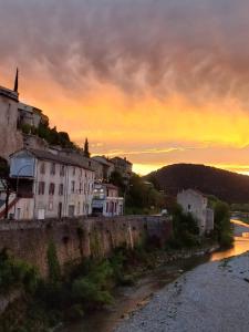 een zonsondergang boven een stad en een rivier met gebouwen bij Sur le Pont in Vaison-la-Romaine