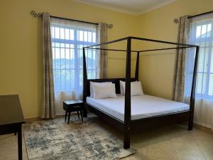 a bedroom with a four poster bed and windows at OLMOTI SUITES in Arusha