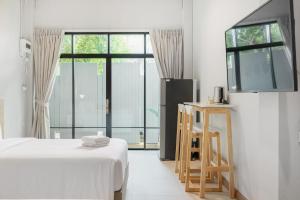 a white bedroom with a bed and a tv at Hotel Wizpark Ratchada in Bangkok