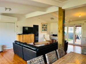 a living room with a black leather couch and a table at Teddy's Shack - Pet Friendly in Robe