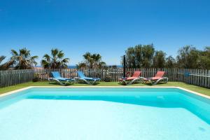 una piscina con dos sillas y una valla en Home2Book Ocean Surf House Fuerteventura, en La Oliva