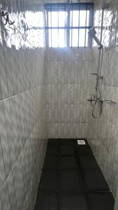 a tiled bathroom with a shower and a window at OLMOTI SUITES in Arusha