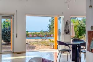 a living room with a table and chairs and a sliding glass door at Meia Lua - Deluxe countryside villa with pool and sea views near Barril beach, Tavira in Luz de Tavira