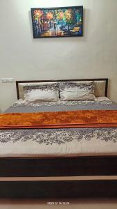 巴羅達的住宿－Gaurang Homestay，卧室内的一张床铺,墙上有绘画作品