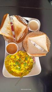 a plate of food with sandwiches and eggs on it at Gaurang Homestay in Vadodara
