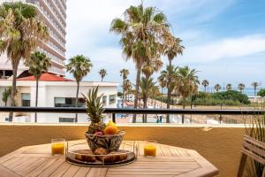 a table with a bowl of fruit on a balcony with palm trees at Charming apartment near beach, sea view terrace in Torremolinos