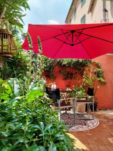 um guarda-chuva vermelho sentado ao lado de uma mesa com um banco em A l'Ombre de la Dame em Cucuron