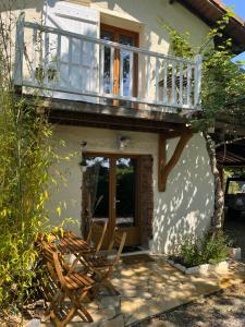 a house with a balcony and two wooden chairs at gîte de Fontjalabert en campagne tout confort in Lisle-sur-Tarn