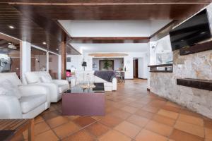 sala de estar con muebles blancos y chimenea de piedra. en Home2Book Ocean Surf House Fuerteventura, en La Oliva