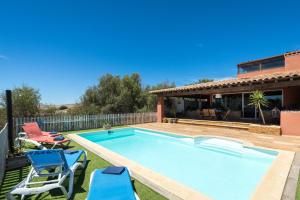 una piscina con dos sillas y una casa en Home2Book Ocean Surf House Fuerteventura, en La Oliva