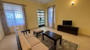 a living room with a couch and a tv at OLMOTI SUITES in Arusha