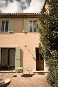 a house with a table in front of a building at La maison du bassin in LʼIsle-sur-la-Sorgue