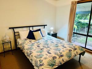 a bedroom with a bed with a floral bedspread at Da Ja Surf - Pet Friendly in Robe