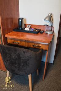 een bureau met een lamp en een stoel in een kamer bij Hotel CARO in Poznań