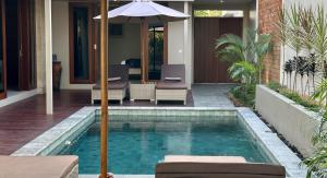 a swimming pool with an umbrella next to a house at Pandan Villas in Selong Belanak