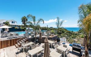 eine Terrasse mit Tischen und Sonnenschirmen und dem Meer in der Unterkunft Cosy Palm Beach Cottage with Spectacular Seaviews in Palm Beach