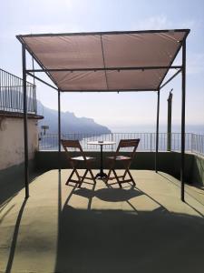 twee stoelen en een tafel onder een luifel op een dak bij Dan Ravello in Ravello