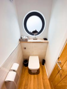 ein kleines Bad mit einem WC und einem runden Fenster in der Unterkunft Rooms at The Deck, Penarth in Cardiff