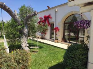 ein Haus mit einem Baum mit Blumen im Hof in der Unterkunft Masseria Salentina Costarella in Borgagne