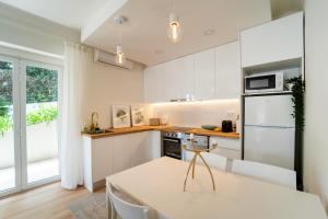 a kitchen with white cabinets and a dining table at Villa Shaz Cascais in Cascais
