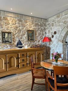 a dining room with a table and a stone wall at Rahoni Park & Suites in Dhërmi
