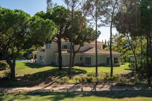 a large white house with trees in the foreground at Casa Atlantico in Quinta do Lago