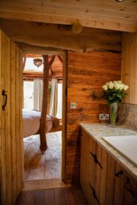 a wooden cabin with a bed and a vase of flowers at Little Hollows Glamping in Little Malvern