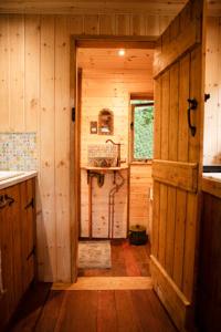 a hallway of a wooden cabin with a sink and a door at Little Hollows Glamping in Little Malvern