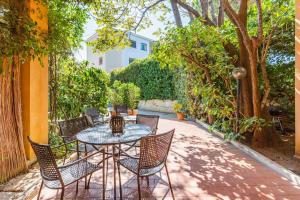 une terrasse avec une table, des chaises et des arbres dans l'établissement mondello sea view beach apartment, à Palerme