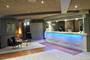 a woman sitting at a bar in a lobby at The Monterey Hotel - Sure Hotel Collection by Best Western in Saint Helier Jersey