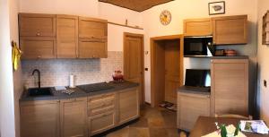a kitchen with wooden cabinets and a sink and a microwave at Residence Dolomiti in Forni di Sopra
