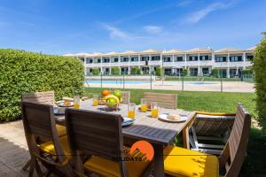 a dining table with chairs in front of a building at #146 Summer House A6 by Home Holidays in Ferreiras