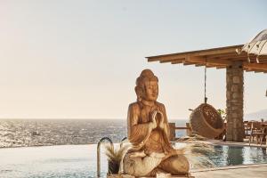 Ubud Mykonos في أغيوس يوانيس ميكونوس: تمثال لسيده جالسه بجانب مسبح