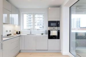 a white kitchen with a sink and a microwave at Cosy 2 bedroom Apartment-Zone 1 in London