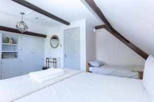 a white bedroom with two beds and a window at The Old Schoolhouse in Whitstable