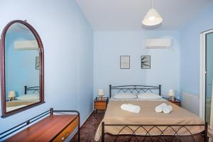 Dormitorio azul con cama y espejo en Aristotelis Apartment Lakithra-Lydia en Lakithra