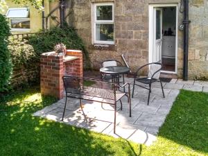 a patio with two chairs and a table in a yard at Beech Cottage in Hepple