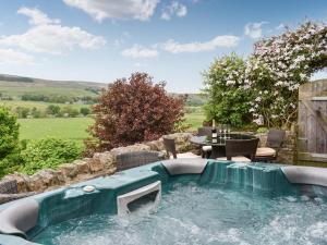 a hot tub in a backyard with a table and chairs at Stoney End Cottage in Askrigg